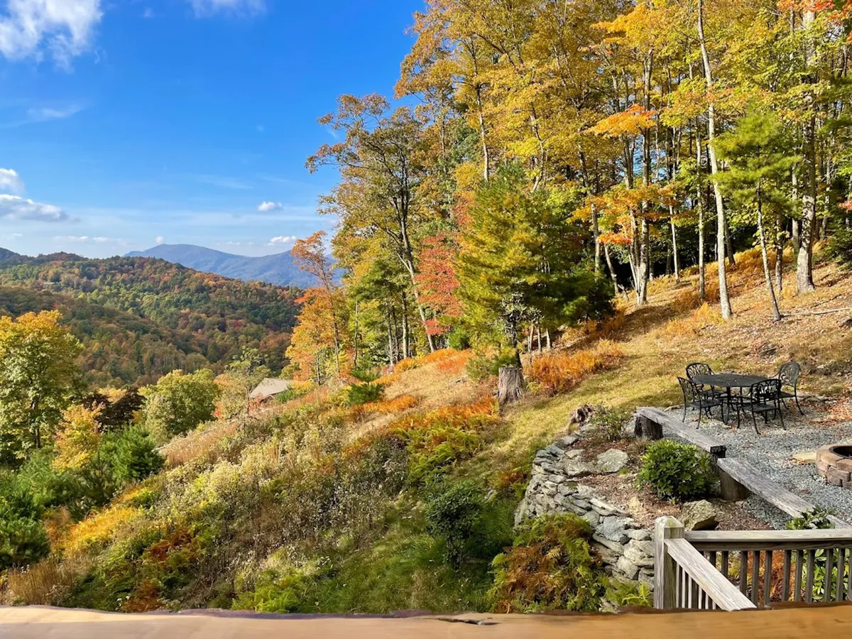 This exterior shot showcases vibrant fall foliage, a wide mountain vista, and an inviting outdoor seating area. The tranquil setting suggests activities like outdoor dining, gathering around the fire pit, and enjoying the changing seasons—perfect for relaxing after a day of exploring local trails and attractions.